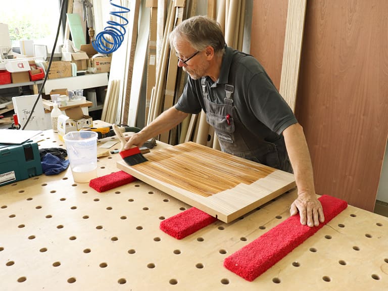 Person lackiert Holz